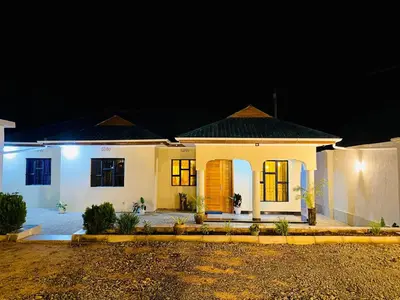 a small white house at night at Amellie's Home Safari in Nkunjila