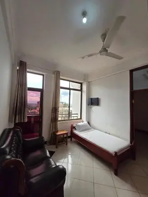 a bedroom with a bed and a couch and windows at Twiga Hotel - Tulivu Urban in Moshi