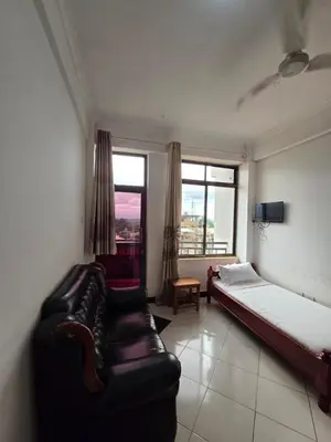 a bedroom with a couch and a bed and a window at Twiga Hotel - Tulivu Urban in Moshi