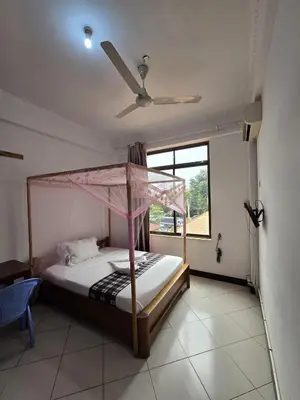 a bedroom with a canopy bed and a window at Twiga Hotel - Tulivu Urban in Moshi