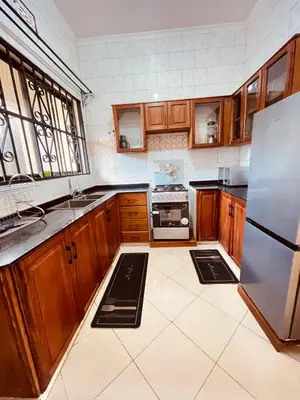 a kitchen with wooden cabinets and a stainless steel refrigerator at D&G Homes Apartments in Arusha