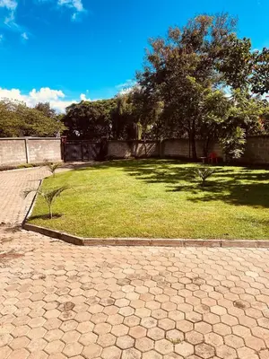 a grassy yard with a fence and trees in it at D&G Homes Apartments in Arusha