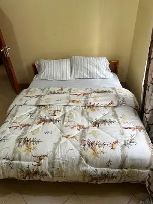 a bed with a white comforter with flowers on it at Vicol luxe stay in Arusha