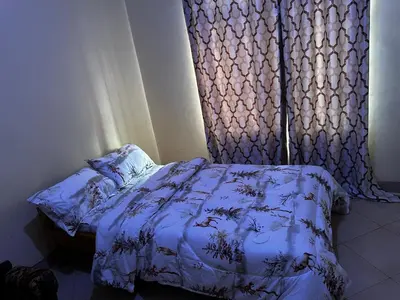 a bedroom with a bed and a window with a curtain at Vicol luxe stay in Arusha