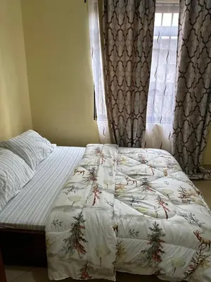 a bed with a white comforter and a window at Vicol luxe stay in Arusha