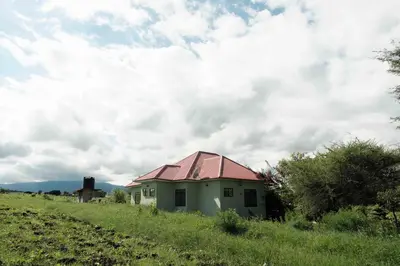 a small house with a red roof in a field at MSOVI Nest in Arusha