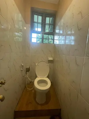 a small bathroom with a toilet with a window at Makahawani Farmhouse in Arusha