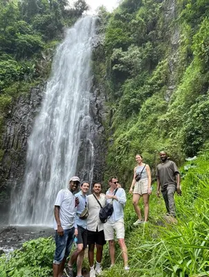 a group of people standing in front of a waterfall at Makahawani Farmhouse in Arusha