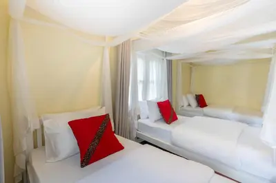 two beds in a room with red and white pillows at Summit Retreat in Moshi
