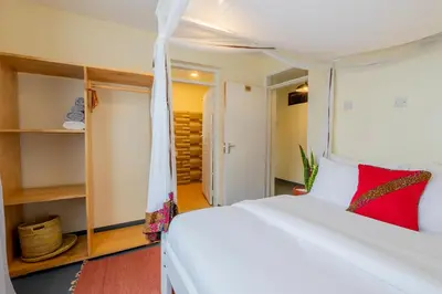 a bedroom with a white bed with a red pillow at Summit Retreat in Moshi