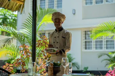 a man in a chefs hat holding a plate of food at Summit Retreat in Moshi