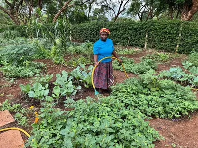 a woman standing in a garden with a hose at Summit Retreat in Moshi