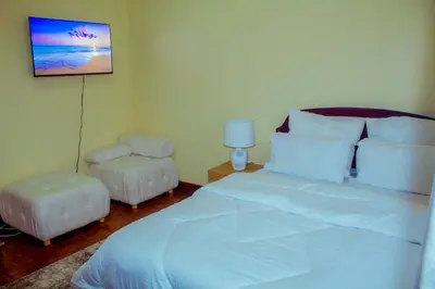 a bedroom with a white bed and a chair at Safari dwells apartment in Arusha