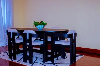 a wooden table with chairs and a vase of flowers on it at Safari dwells apartment in Arusha