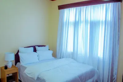 a bedroom with a bed and a window with white curtains at Safari dwells apartment in Arusha