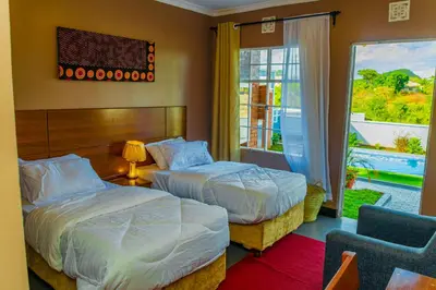 a hotel room with two beds and a window at Geni's Villa & Spa Arusha in Arusha