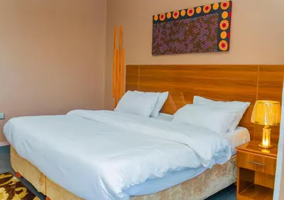 a bedroom with two beds and a painting on the wall at Geni's Villa & Spa Arusha in Arusha