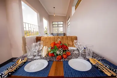 a table with two plates and a vase of flowers on it at Geni's Villa & Spa Arusha in Arusha
