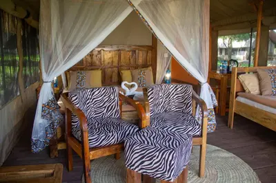 a room with two chairs and a bed in a tent at Africa Safari Manyara Escarpment in Mto wa Mbu