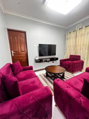 a living room with purple couches and a tv at Hadraj Moshono Apartment2 in Arusha