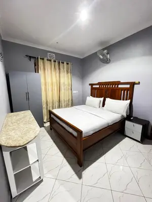 a bedroom with a bed and a table in it at Hadraj Moshono Apartment2 in Arusha