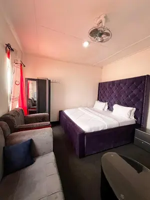 a bedroom with a large bed and a couch at Hadraj Sokokuu Apartment2 in Arusha