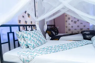 a bedroom with two beds and a canopy at Rosemo villa in Nduruma Chini