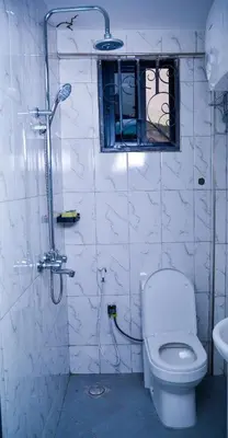 a white bathroom with a toilet and a window at The Hill Villas House in Arusha