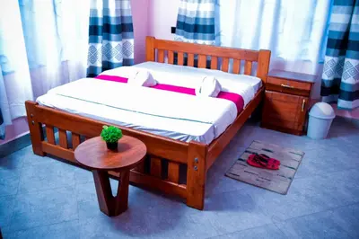 a small wooden bed in a room with a table at The Hill Villas House in Arusha