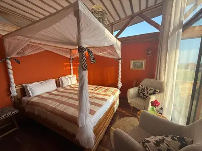 a bedroom with a canopy bed and a chair at Moyoni Africa Lodge & Tours in Arusha