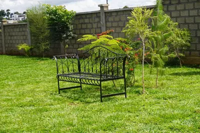 a metal bench sitting in the grass in a yard at Moyoni Africa Lodge & Tours in Arusha