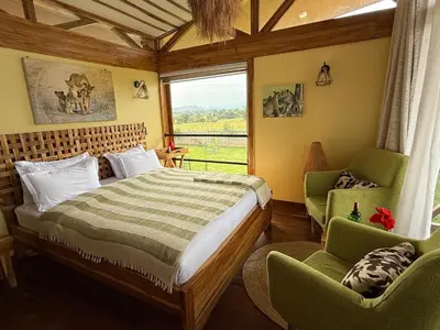 a bedroom with a bed and two chairs and a window at Moyoni Africa Lodge & Tours in Arusha