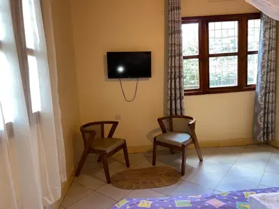 a living room with two chairs and a tv on the wall at Nyani's hub in Moshi
