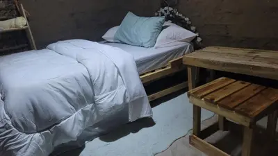 a bed with a blue pillow and a wooden table at Kidep Maasai Village in Moshi