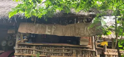 a thatch roofed hut with a sign on it at Kidep Maasai Village in Moshi