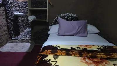 a bedroom with a bed with purple pillows at Kidep Maasai Village in Moshi