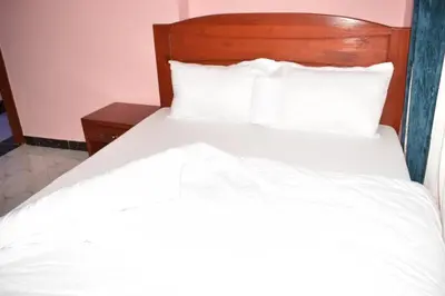 a bed with white sheets and pillows in a room at Volunteer House in Msaranga