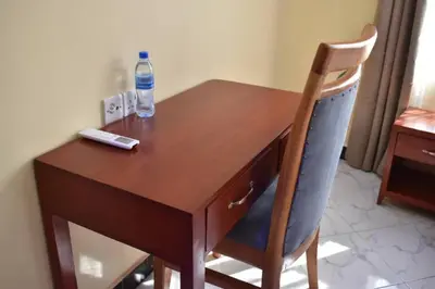a wooden desk with a remote control and a bottle of water at Volunteer House in Msaranga