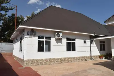 a white house with a black roof at Volunteer House in Msaranga