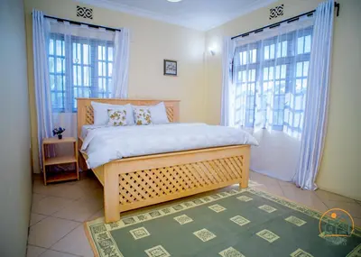 a bedroom with a large bed and two windows at Oasis Homestay in Arusha