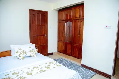 a bedroom with a bed and wooden cabinets at Oasis Homestay in Arusha