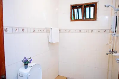a white bathroom with a toilet and a window at Oasis Homestay in Arusha