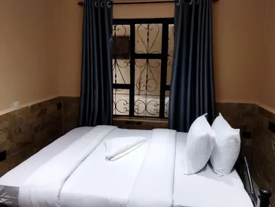 a bed with white sheets and pillows in front of a window at Moonshine hotel in Themi