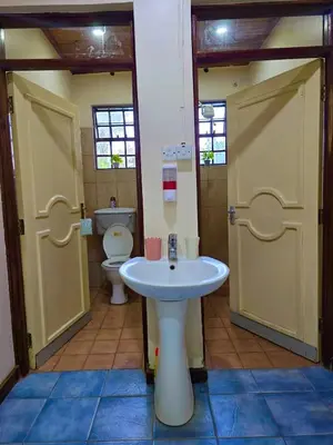 a bathroom with a toilet and a sink and two doors at 2 bedrooms cozy house in Arusha in Arusha
