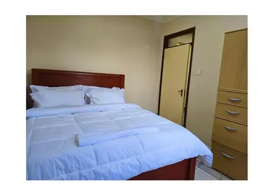 a bedroom with a large white bed and a dresser at 2 bedrooms cozy house in Arusha in Arusha