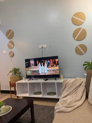 a living room with a flat screen tv on a white entertainment center at Amaroz House in Nkunjila