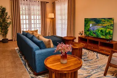 a living room with a blue couch and tables at Fusion of Style & Comfort in Arusha
