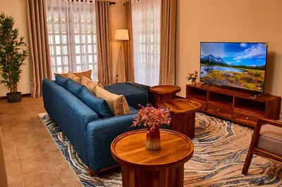 a living room with a blue couch and a tv at Fusion of Style & Comfort in Arusha