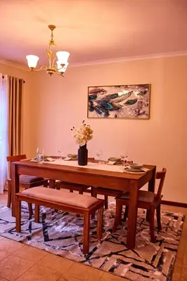 a dining room with a wooden table and chairs at Fusion of Style & Comfort in Arusha