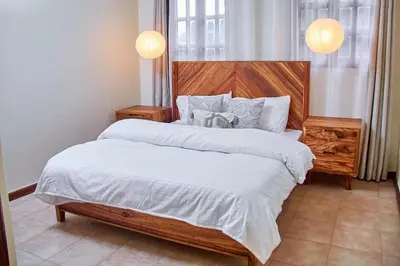 a bedroom with a large bed with a wooden headboard at Fusion of Style & Comfort in Arusha